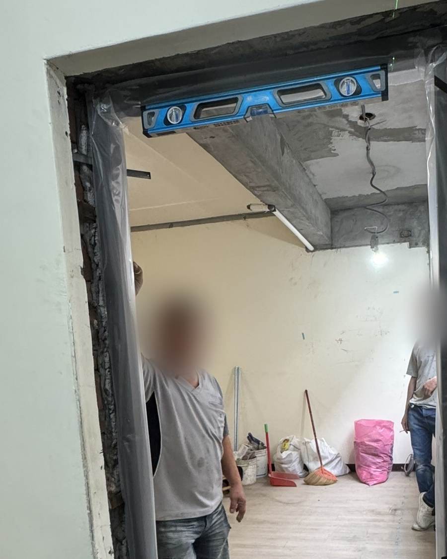 壓花門組610 安裝現場:新門框剛立好,一把水平尺壓在上框,門片還沒掛上