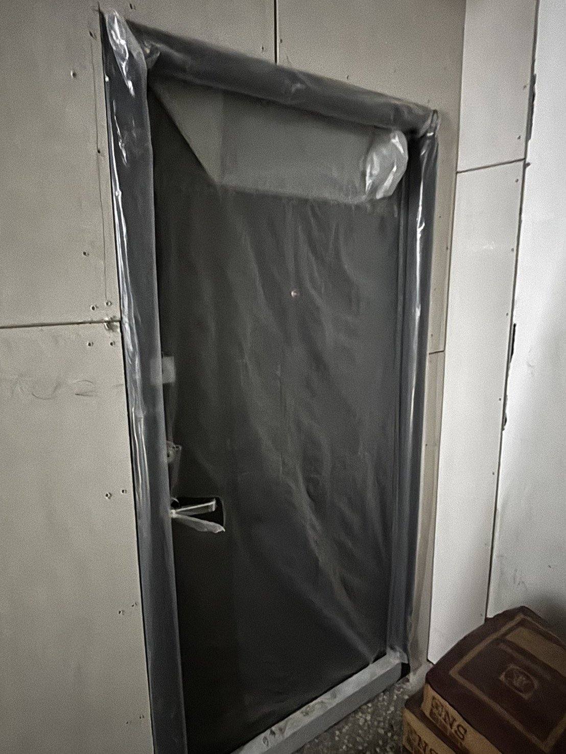 同一樘硫化銅門打開,門後是還在施工的室內,地上堆著水泥